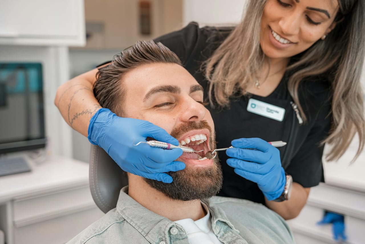 A patient relaxed in the chair while a clinician carries out a professional hygiene appointment